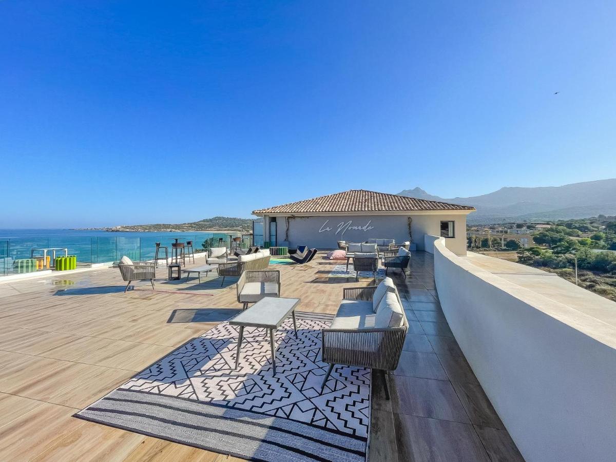 un balcon avec des chaises et des tables sur un immeuble dans l'établissement Eco-Résidence Dolce Paese & Spa, à Algajola un balcon avec des chaises et des tables sur un immeuble dans l'établissement Eco-Résidence Dolce Paese & Spa, à Algajola