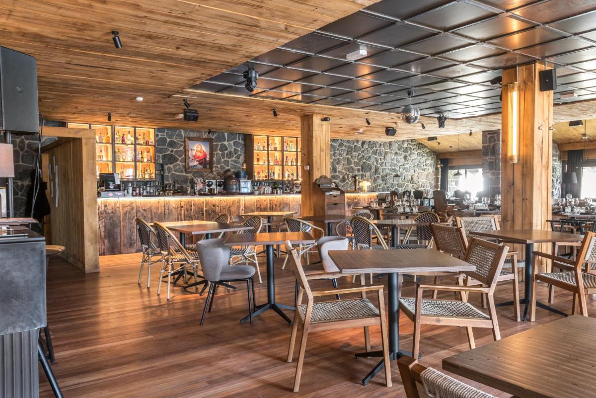 Un restaurante con mesas y sillas y un bar. en Snö Hotel Formigal, en Formigal
