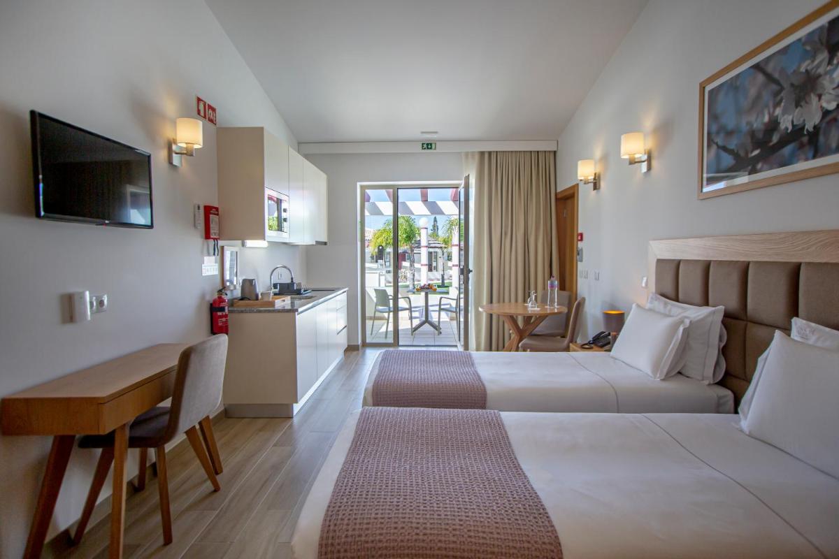 um quarto de hotel com duas camas e uma escrivaninha em Hotel Rural Brícia Du Mar em Ferragudo