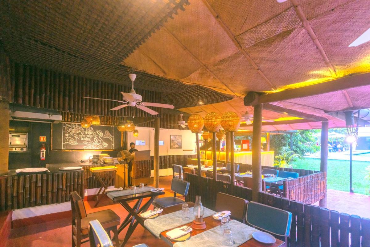 a restaurant with tables and chairs and a ceiling fan at Casino Hotel - CGH Earth, Cochin in Cochin