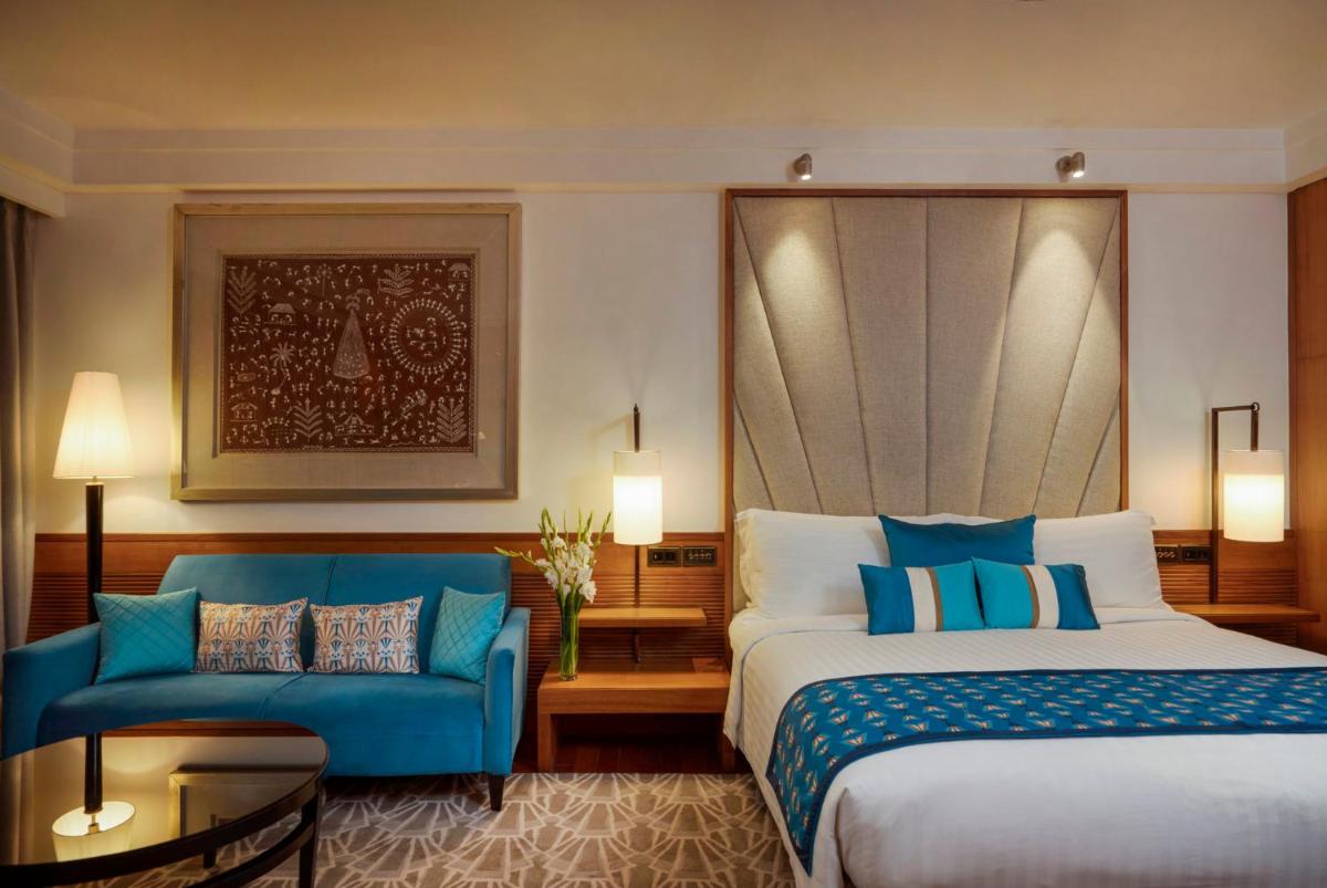 a hotel room with a bed and a blue couch at InterContinental Marine Drive Mumbai by IHG in Mumbai