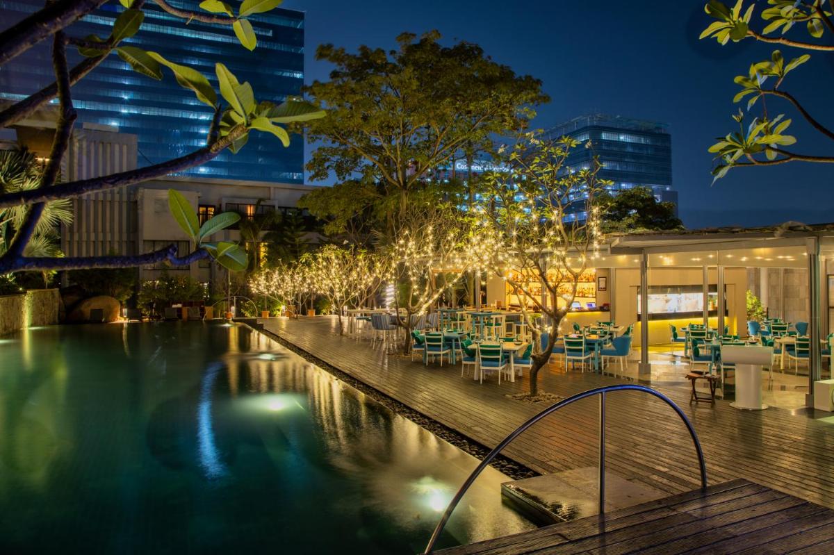 a hotel pool with tables and chairs at night at Hyatt Hyderabad Gachibowli in Hyderabad