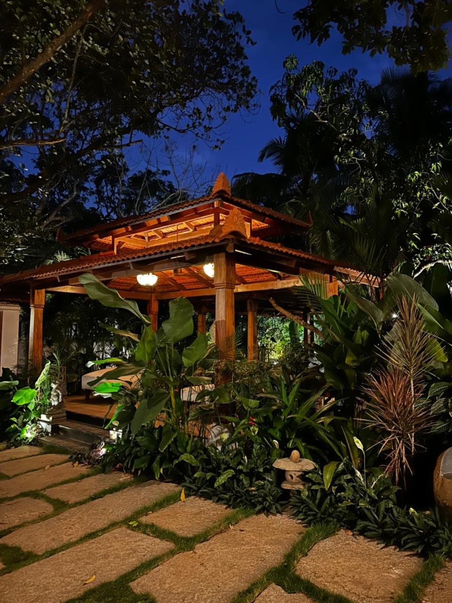 a wooden pergola in a garden at night at The Postcard Saligao in Calangute