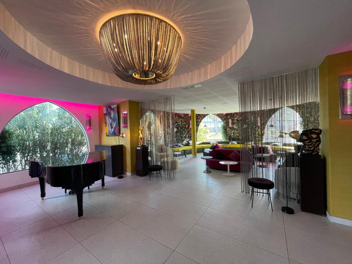 - un hall avec un grand lustre, des tables et des chaises dans l'établissement Oz'Inn Hôtel & Spa, au Cap d'Agde