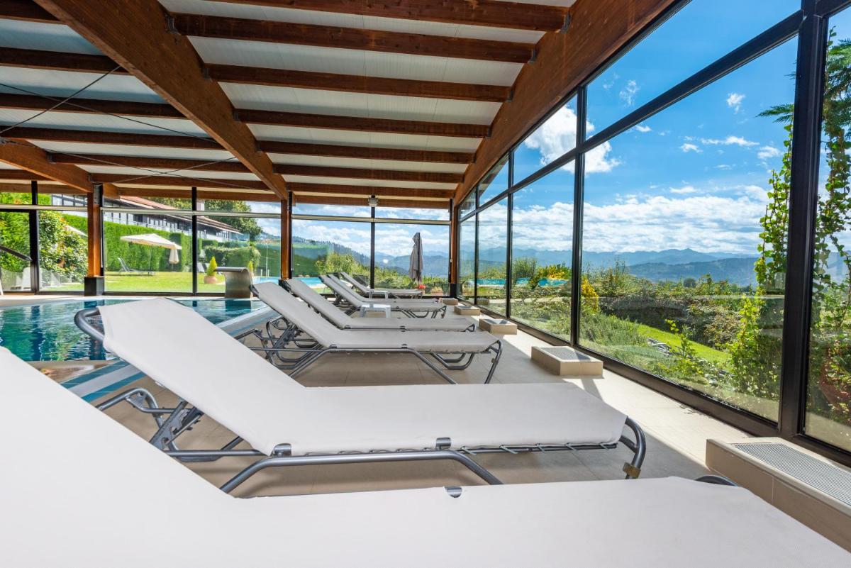 una sala de estar abierta con piscina y paredes de cristal. en Hosteria de Torazo Nature Hotel & Spa, en Torazo