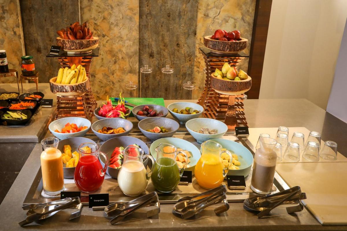a table with plates of food and bowls of fruit at Radisson Blu Hotel & Suites GRT Chennai in Chennai