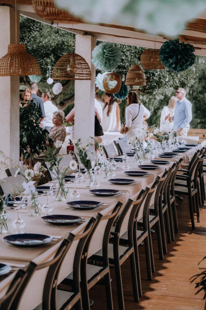 une longue table avec des chaises et des personnes à un mariage dans l'établissement Hôtel Beau Site, au Lavandou