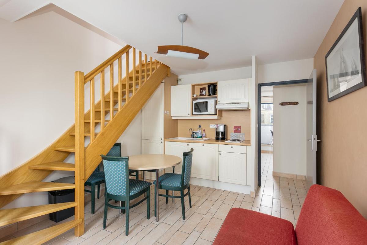 un salon avec une table et des chaises et un escalier dans l'établissement Résidence Bellevue, à Camaret-sur-Mer