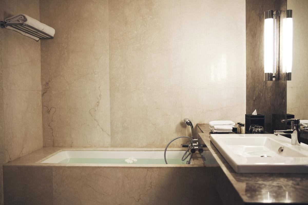 a bathroom with a bath tub and a sink at The Anya Hotel-Golf Course Road in Gurgaon