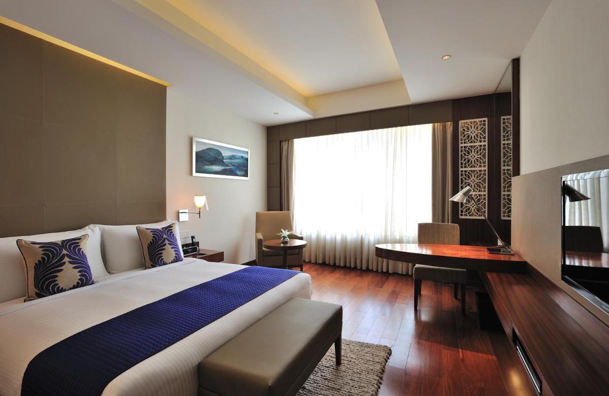 a bedroom with a bed and a desk and a window at The Anya Hotel-Golf Course Road in Gurgaon