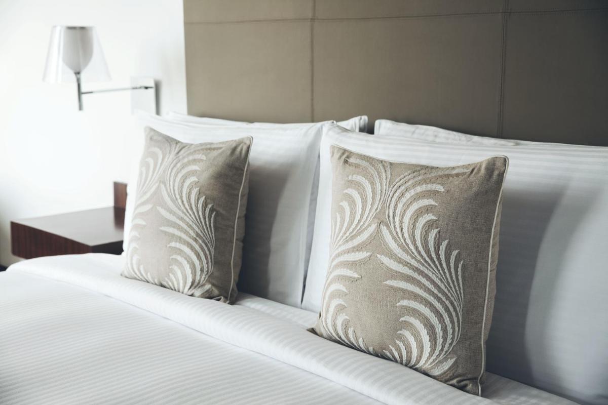 a bed with white sheets and pillows at The Anya Hotel-Golf Course Road in Gurgaon