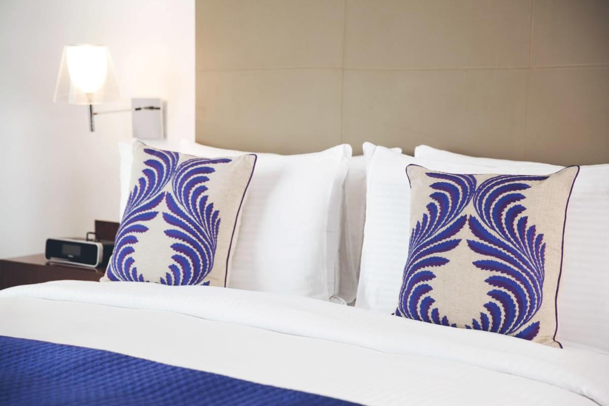 a bed with blue and white pillows on it at The Anya Hotel-Golf Course Road in Gurgaon