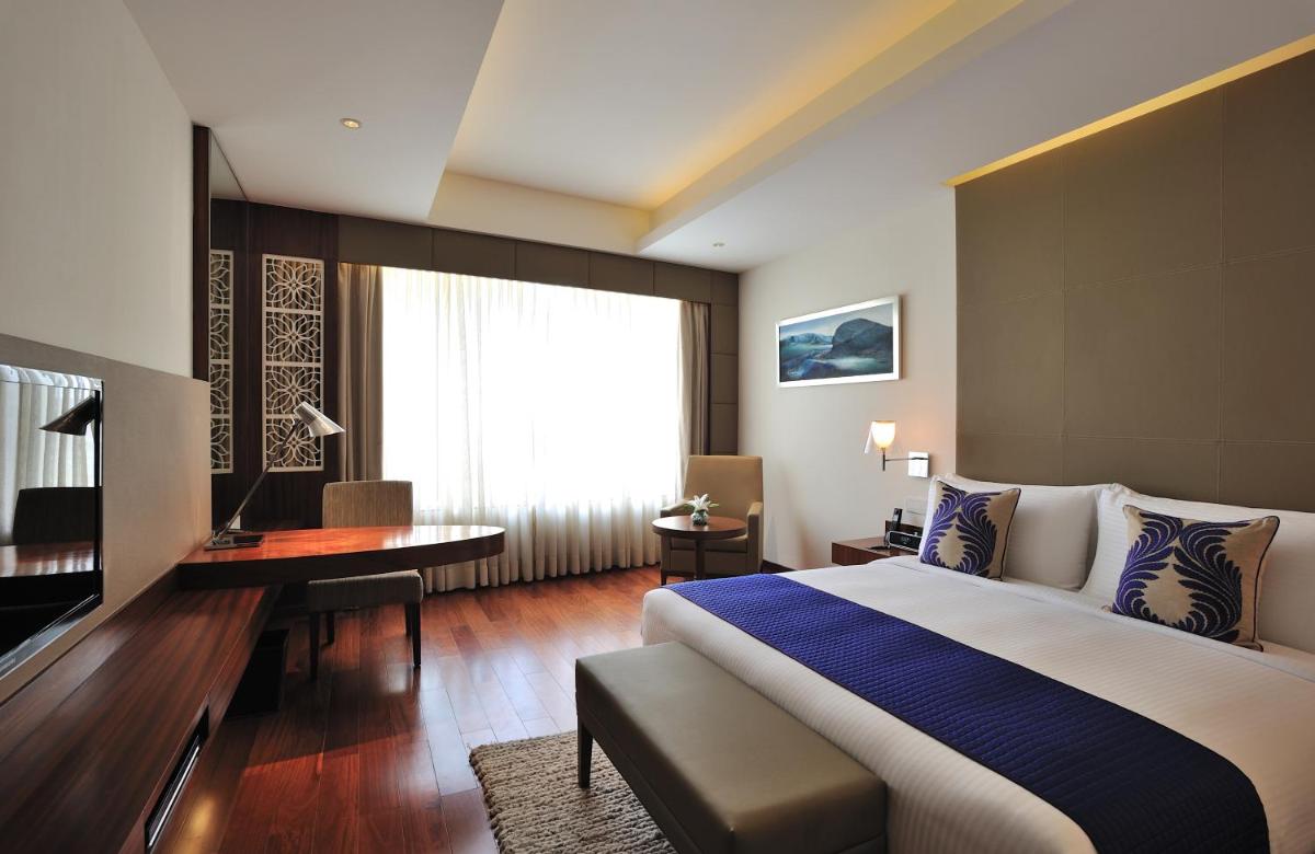 a hotel room with a large bed and a desk at The Anya Hotel-Golf Course Road in Gurgaon