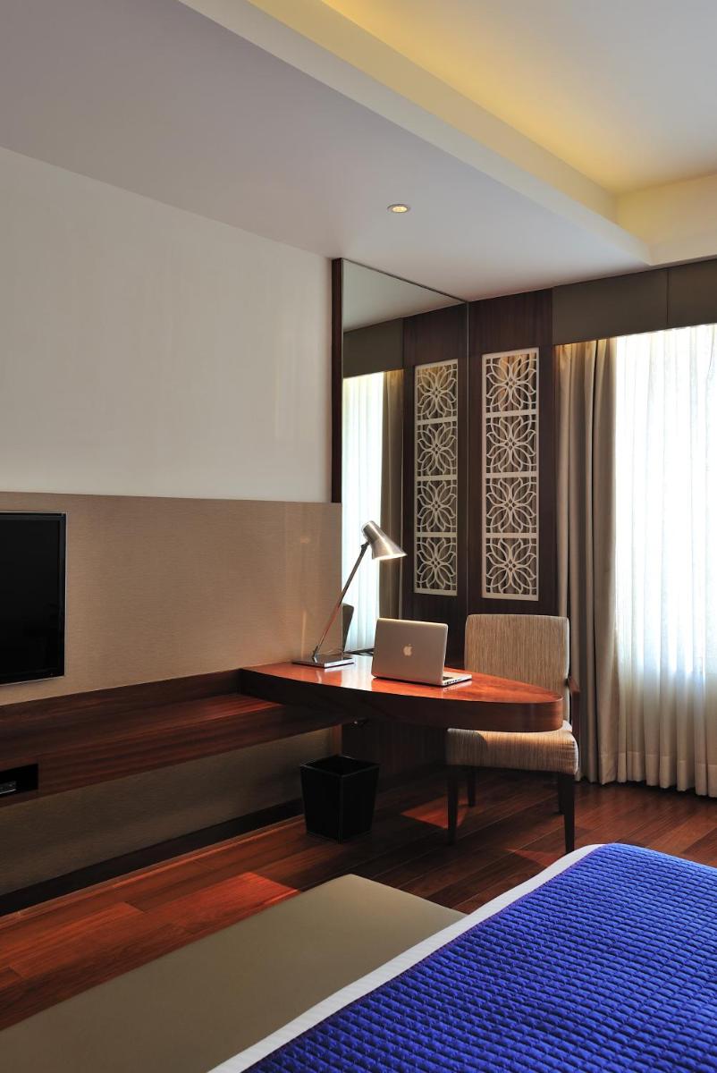 a bedroom with a desk with a laptop and a television at The Anya Hotel-Golf Course Road in Gurgaon