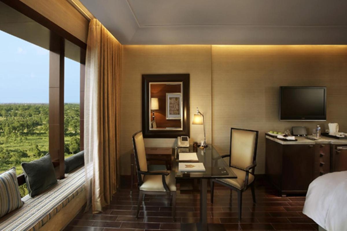 a hotel room with a desk and a bed at The Leela Ambience Gurugram Hotel & Residences - The Luxury Urban Sanctuary in Gurgaon