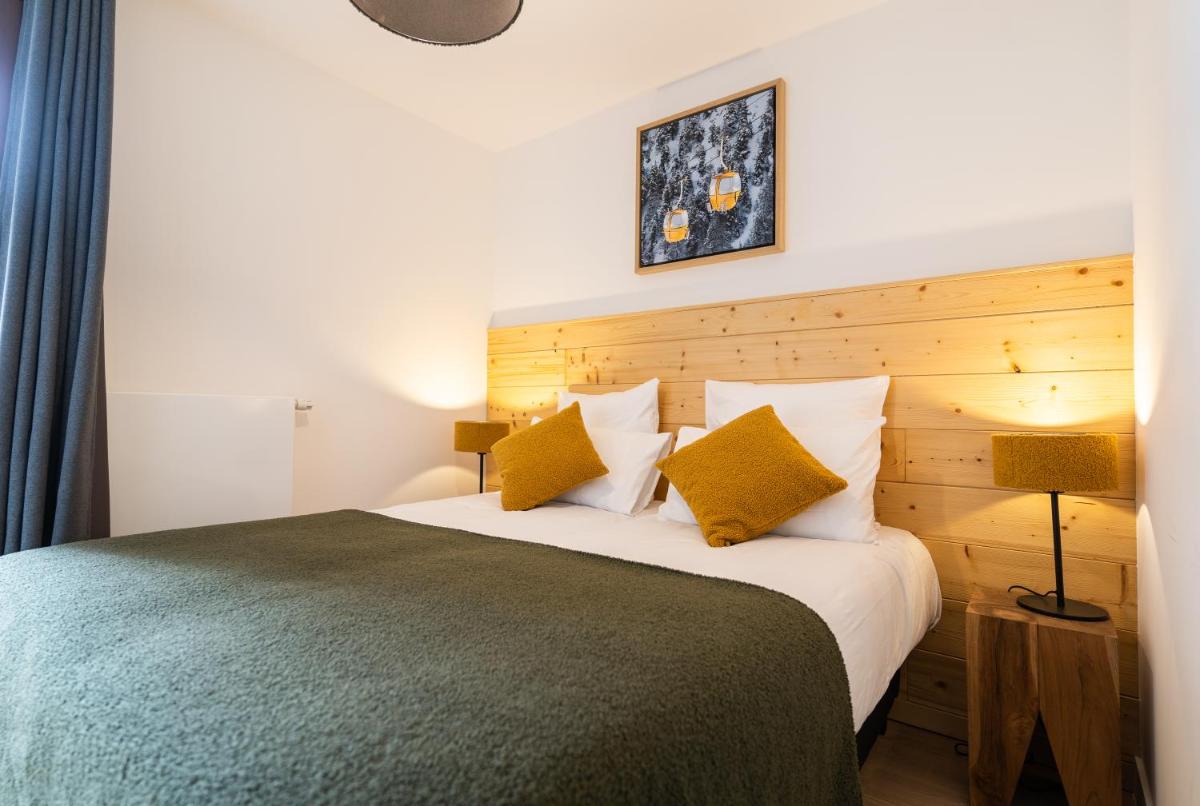 une chambre avec un grand lit aux oreillers jaunes dans l'établissement Les Roches du Mont Blanc - Résidence & Spa, à Combloux
