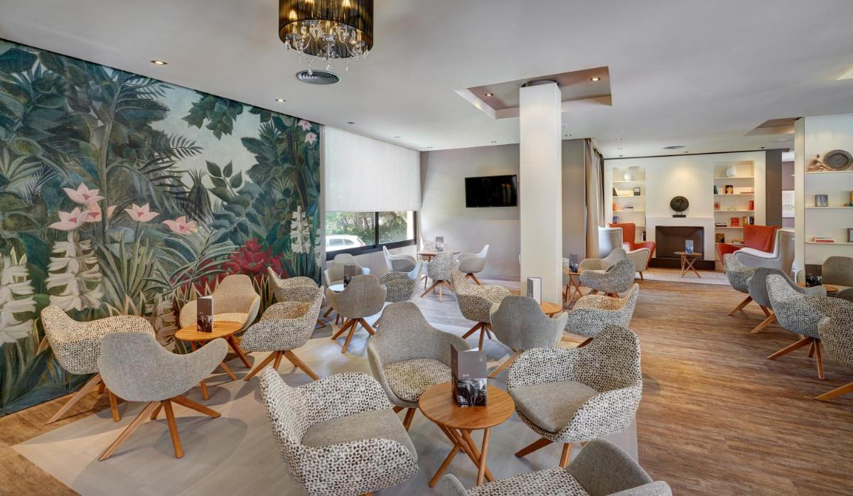 una sala de espera con sillas y mesas y un mural en Protur Turo Pins 4* SUP, en Cala Ratjada