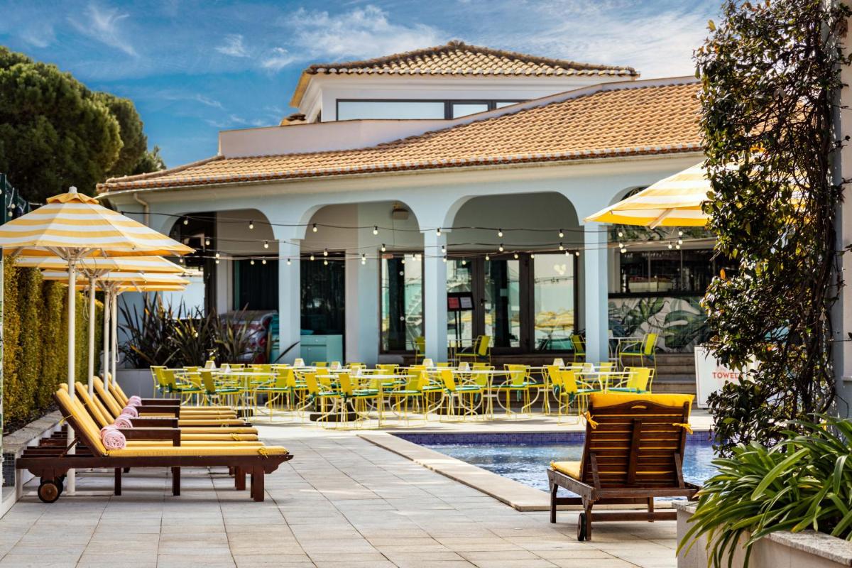 um resort com cadeiras e mesas amarelas e uma piscina em The Magnolia Hotel na Quinta do Lago