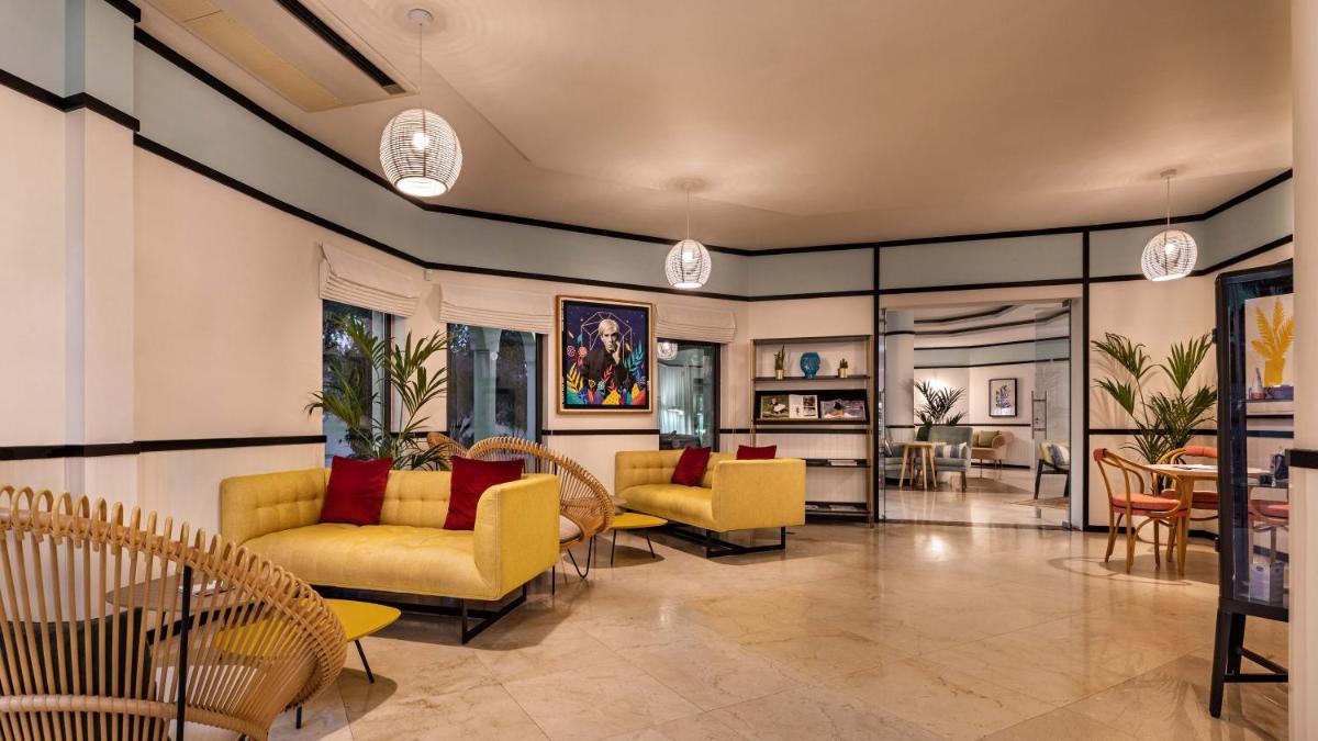 uma sala de estar com cadeiras e mesas amarelas em The Magnolia Hotel na Quinta do Lago