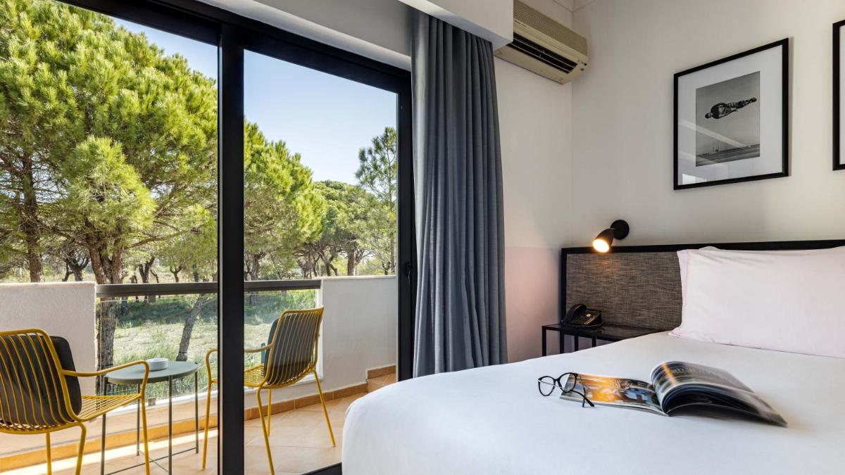 um quarto com uma cama e uma janela grande em The Magnolia Hotel na Quinta do Lago
