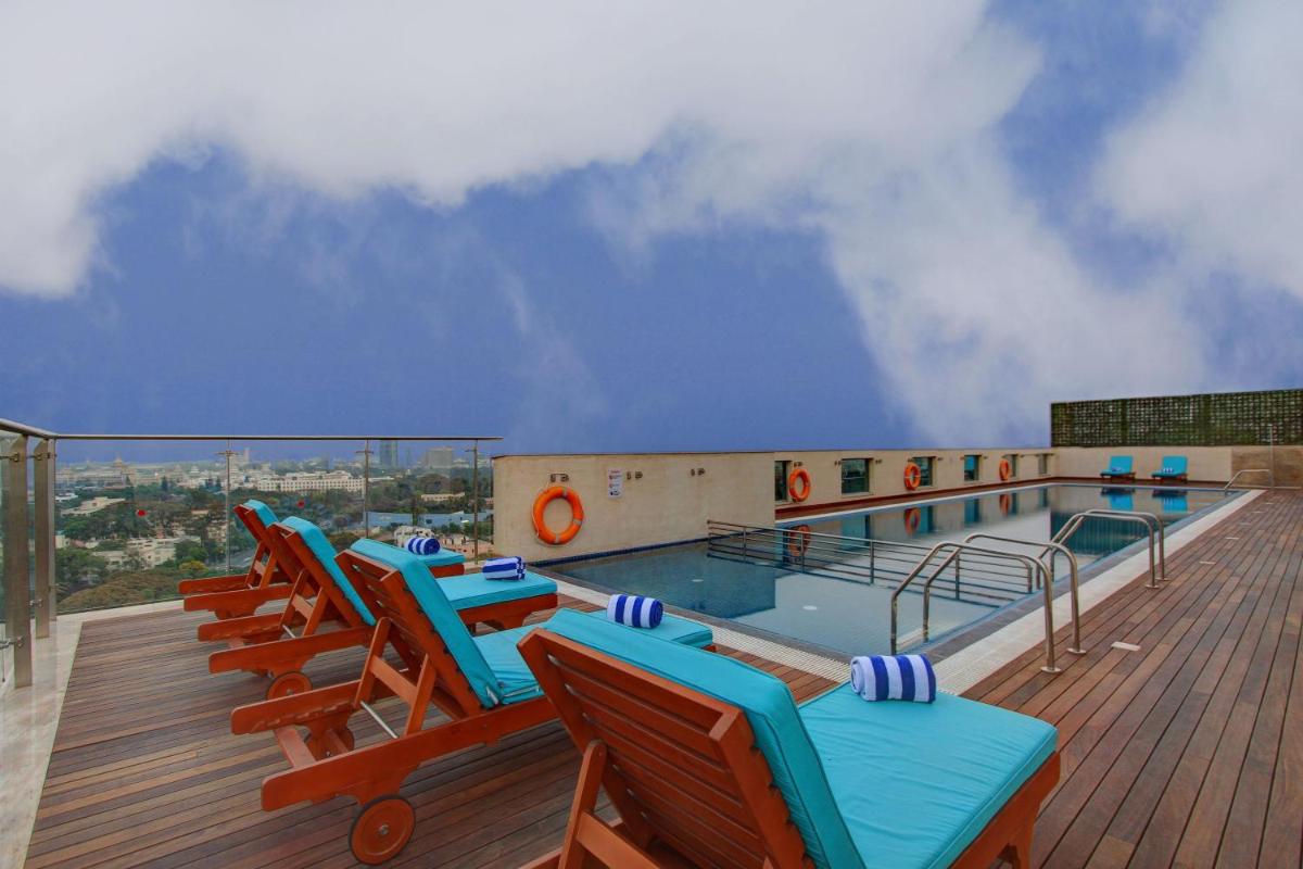a deck with chairs and a swimming pool on a building at Holiday Inn Bengaluru Racecourse by IHG in Bengaluru a deck with chairs and a swimming pool on a building at Holiday Inn Bengaluru Racecourse by IHG in Bengaluru