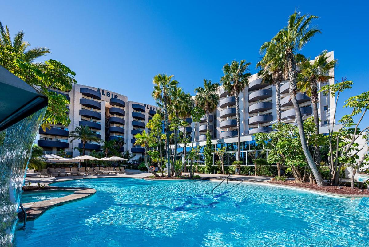 Una piscina con palmeras frente a un hotel. en Albir Playa Hotel & Spa, en Albir