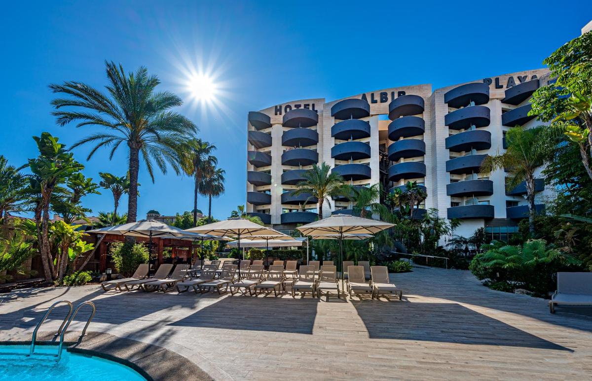 un complejo con piscina y sillas y un hotel en Albir Playa Hotel & Spa, en Albir