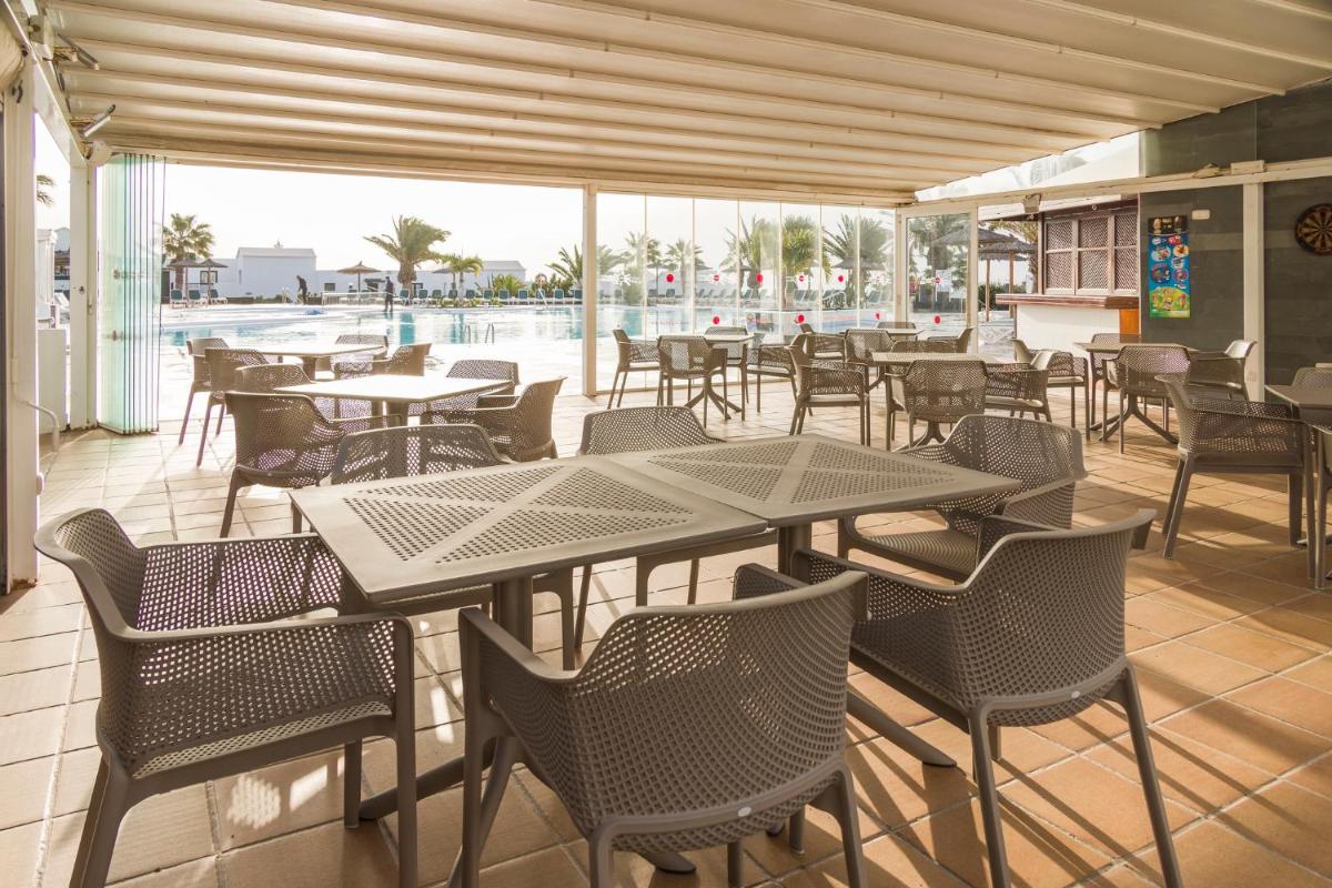 Un restaurante con mesas y sillas y una piscina. en ILUNION Costa Sal Lanzarote, en Puerto del Carmen