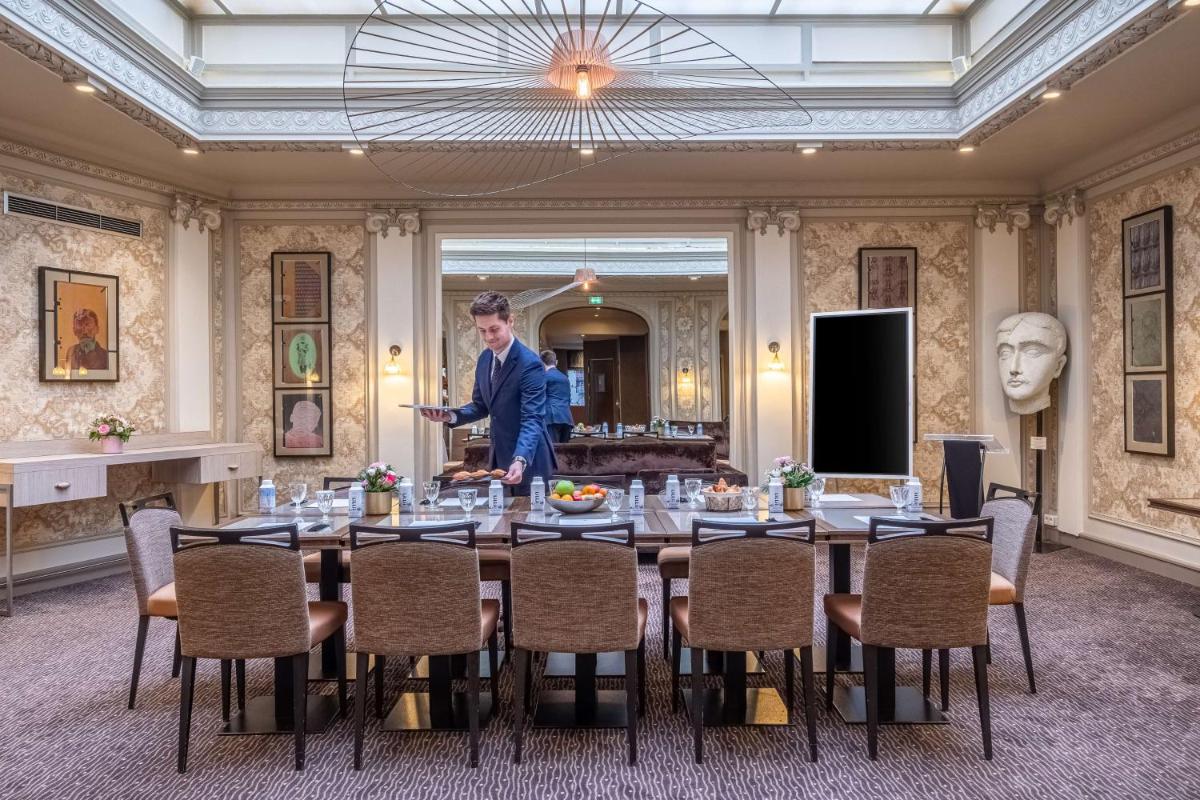 un homme debout devant une table dans une pièce dans l'établissement Hotel Litteraire Le Swann, BW Premier Collection, à Paris