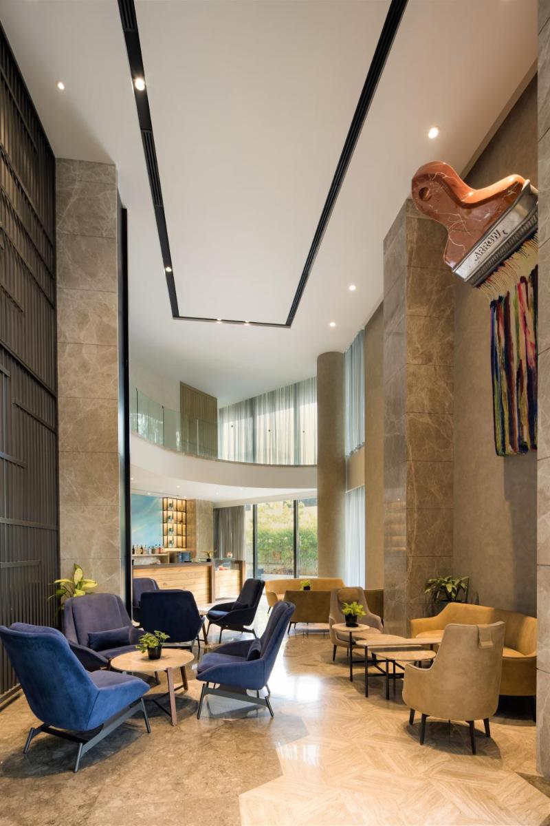 a lobby with chairs and tables in a building at Radisson Blu Mumbai International Airport in Mumbai a lobby with chairs and tables in a building at Radisson Blu Mumbai International Airport in Mumbai