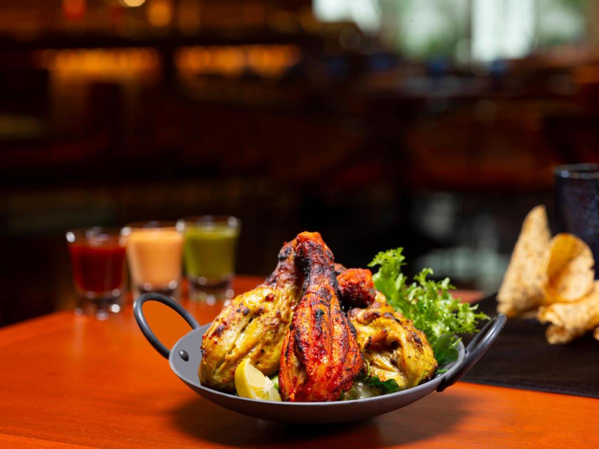 a plate of food with chicken and broccoli on a table at Radisson Blu Hotel & Suites GRT Chennai in Chennai
