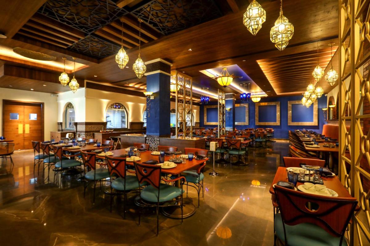 a dining room with tables and chairs and chandeliers at Radisson Blu Hotel & Suites GRT Chennai in Chennai