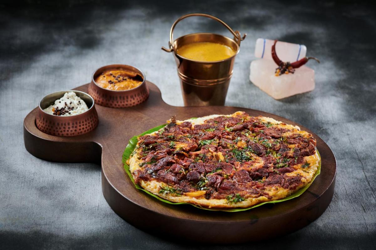 a pizza sitting on top of a wooden cutting board at Radisson Blu Hotel & Suites GRT Chennai in Chennai