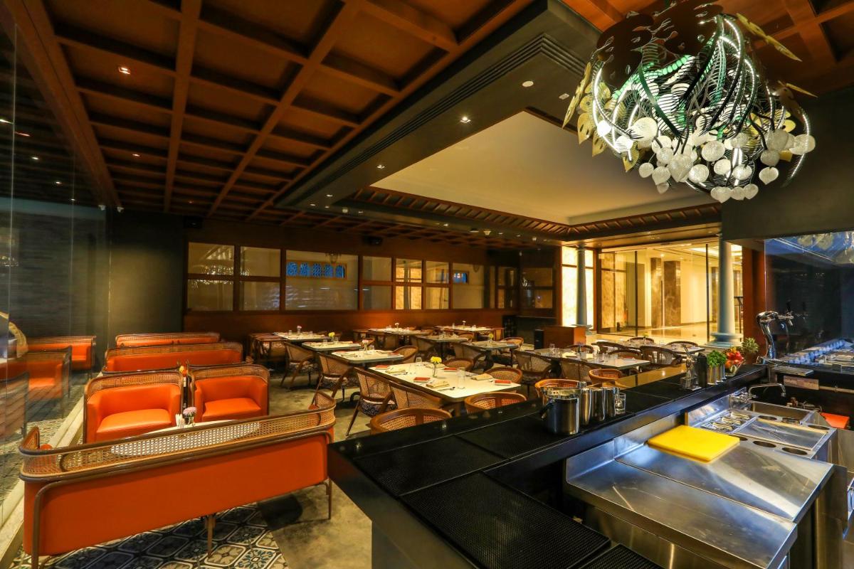 a restaurant with tables and chairs and a chandelier at Radisson Blu Hotel & Suites GRT Chennai in Chennai