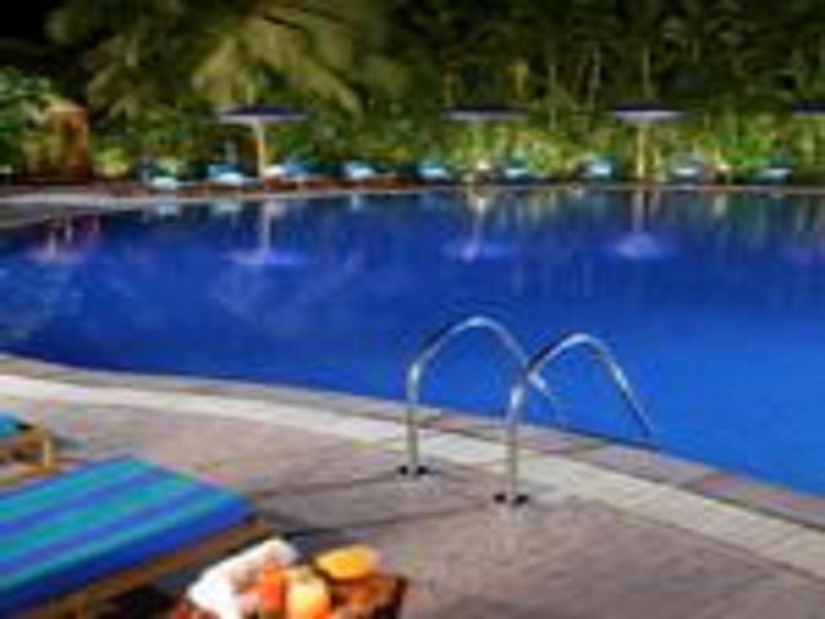 a blue swimming pool with a bench and a table at The Lalit Mumbai in Mumbai
