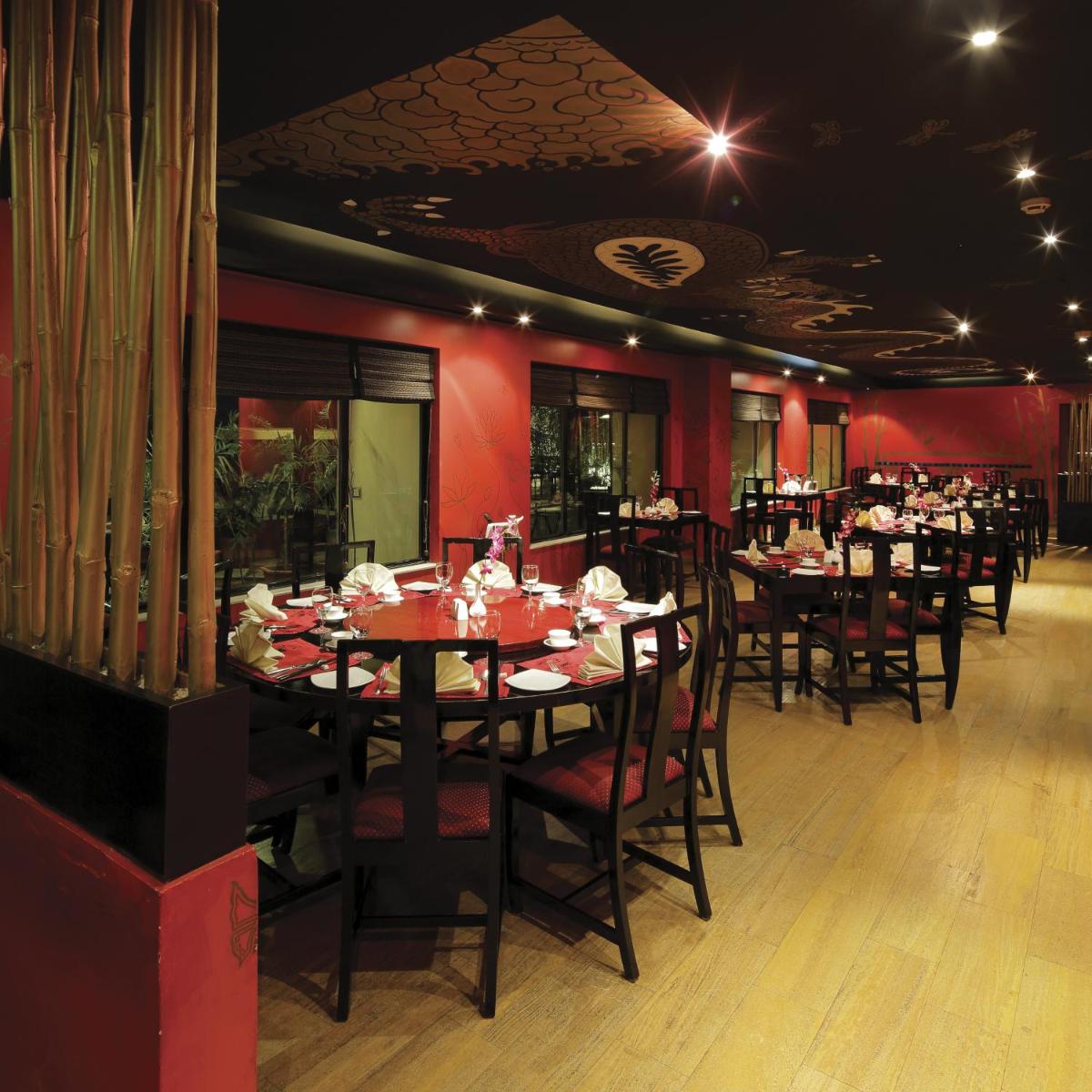 a dining room with tables and chairs and red walls at Radisson Jaipur City Center in Jaipur