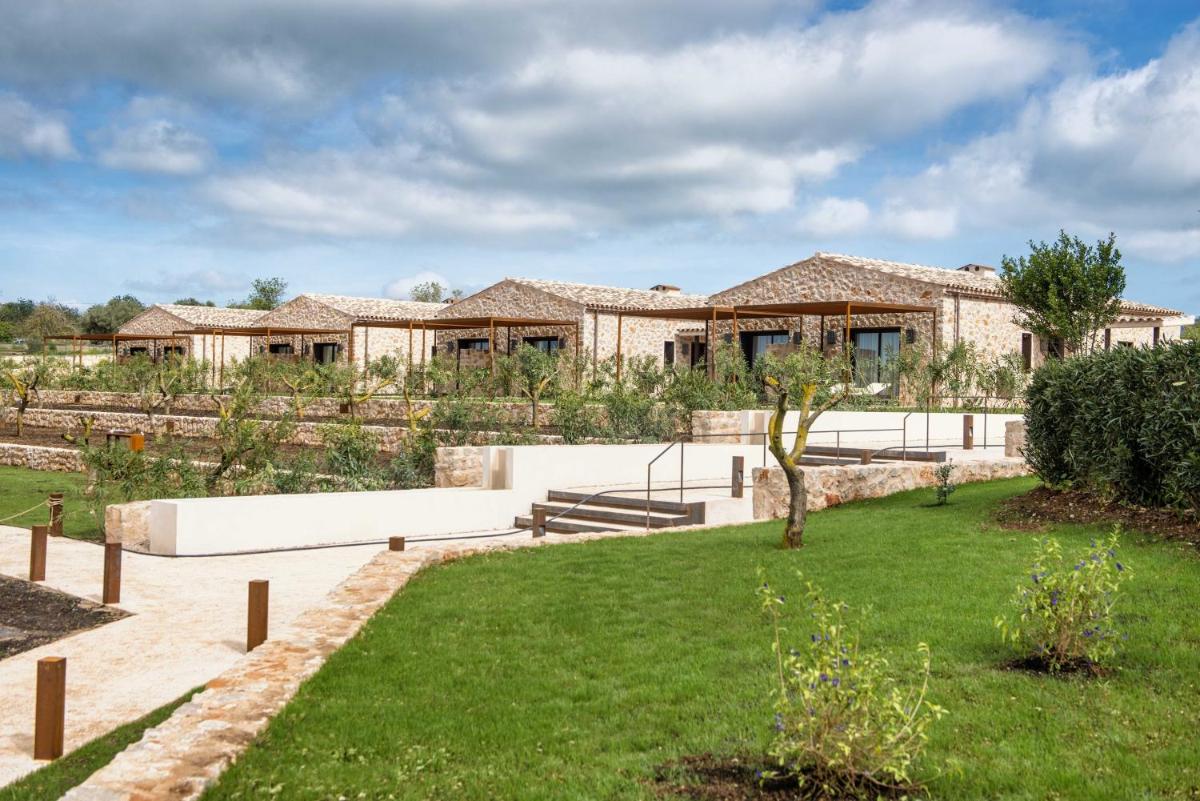 Una casa con un césped verde delante de ella. en Hotel Son Trobat Wellness & Spa, en Sant Llorenç des Cardassar