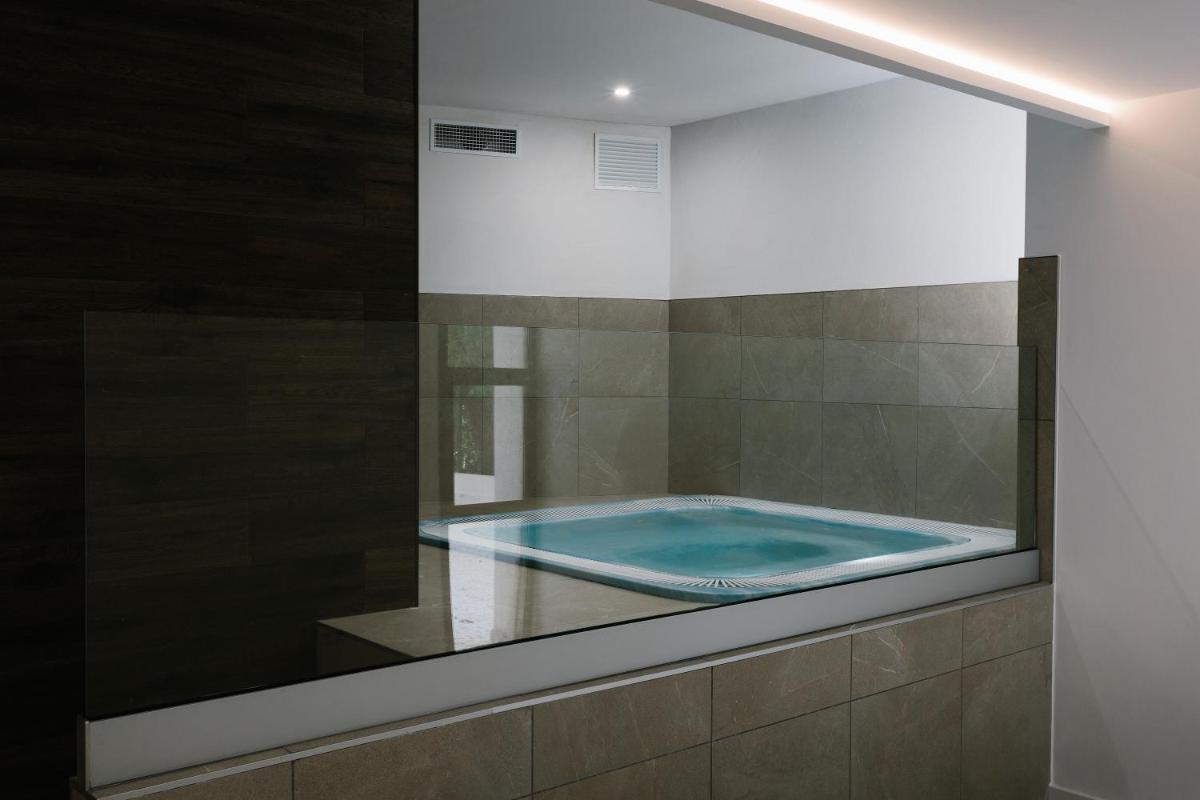 Una piscina con una ventana de cristal en un baño. en Bordoy Alcudia Bay - Adults Only, en Puerto de Alcudia