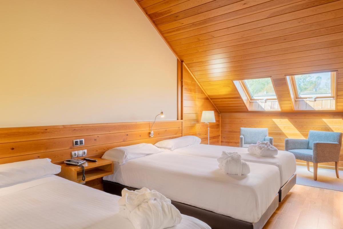 una habitación de hotel con dos camas y una silla en IBERIK Augas Santas Balneario & Golf, en Pantón 62 fotos más