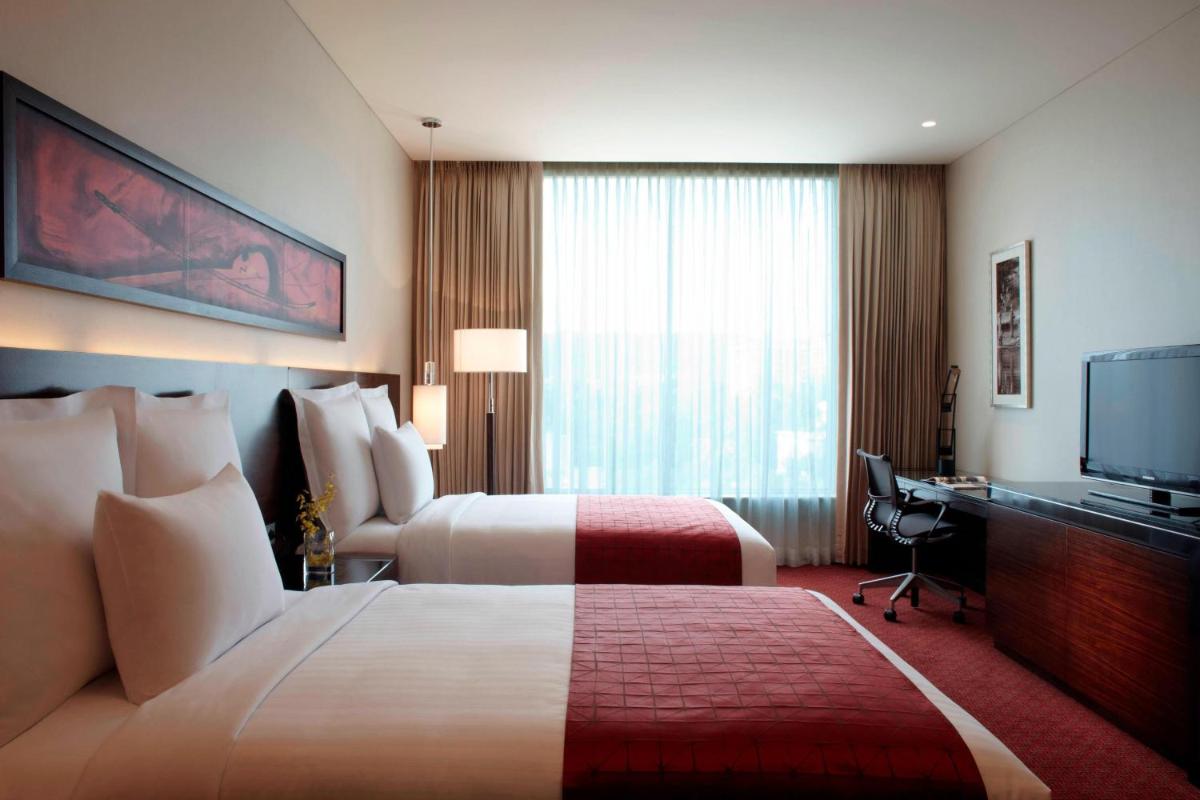a hotel room with two beds and a flat screen tv at JW Marriott Pune in Pune