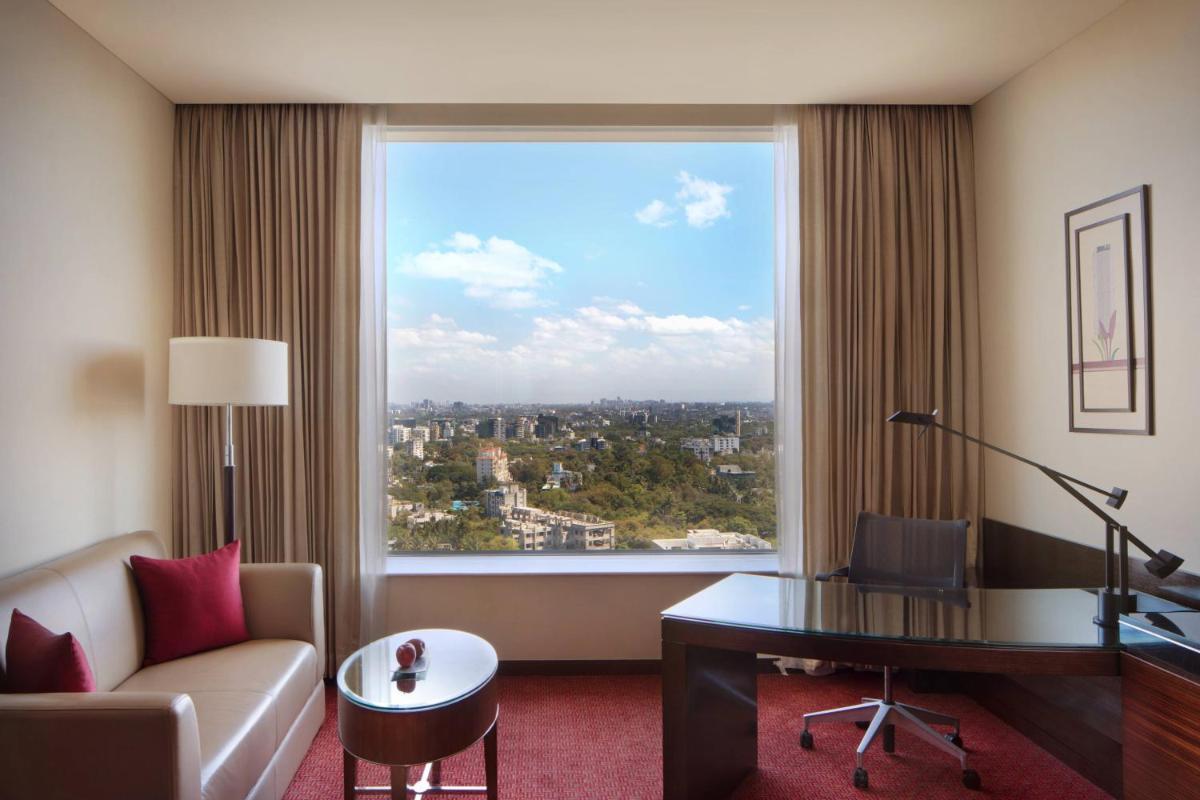 a hotel room with a desk and a large window at JW Marriott Pune in Pune