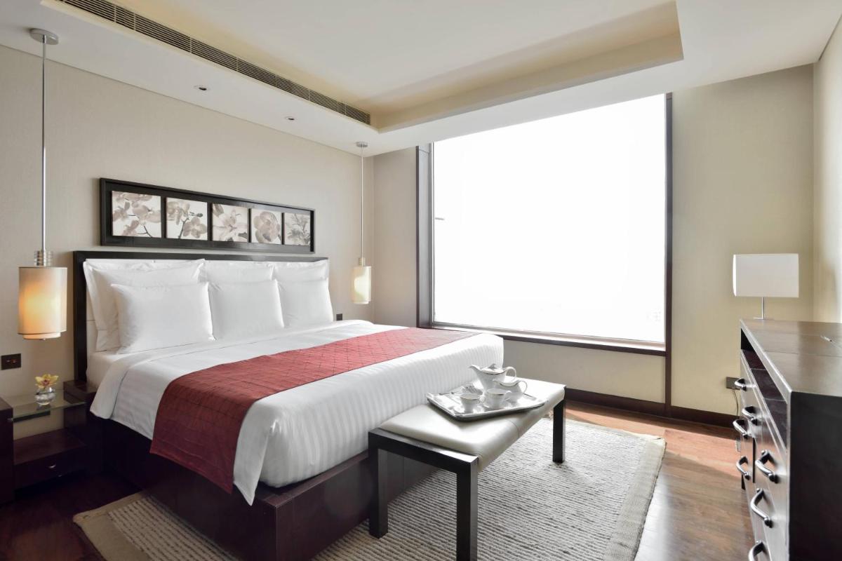 a bedroom with a large bed and a large window at JW Marriott Pune in Pune