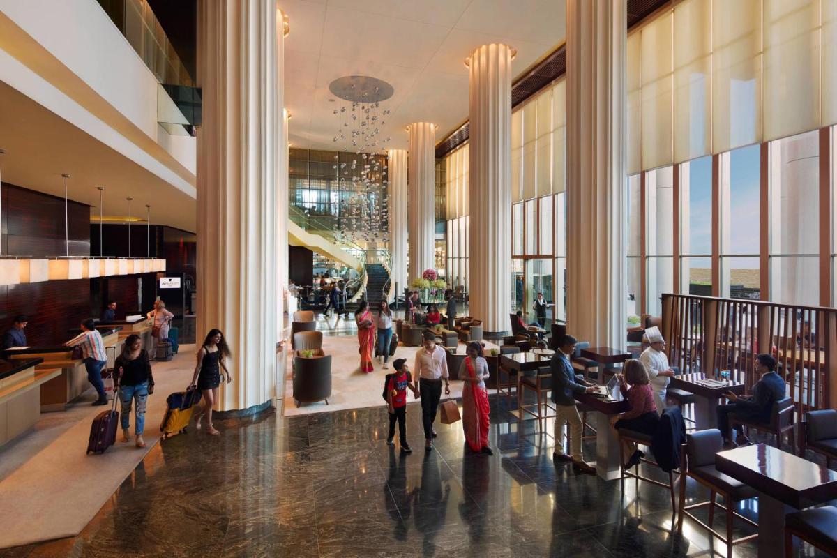 a group of people walking through a lobby at JW Marriott Pune in Pune