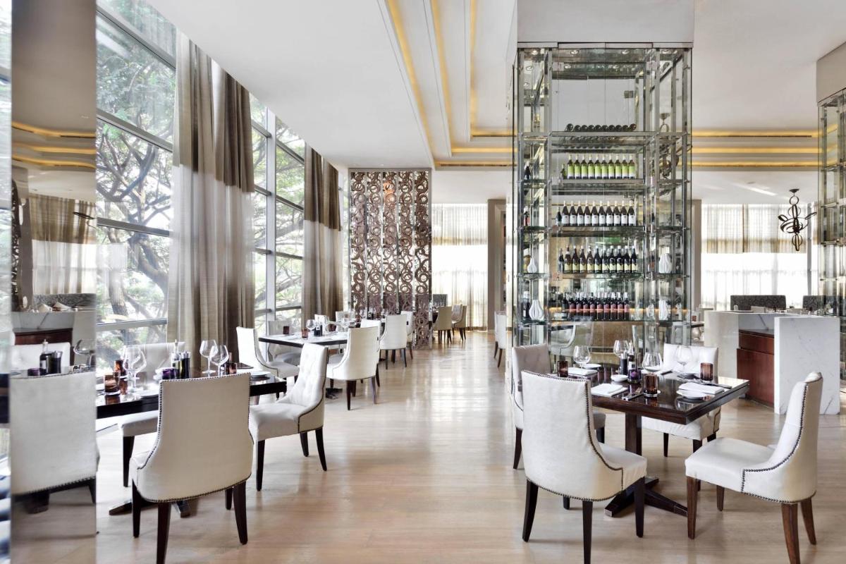 a dining room with tables and white chairs and windows at JW Marriott Pune in Pune