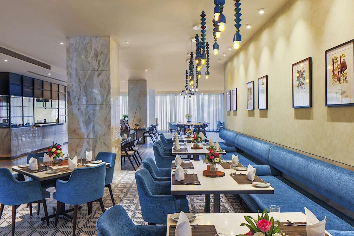 a restaurant with long tables and blue chairs at Radisson Blu Mumbai International Airport in Mumbai a restaurant with long tables and blue chairs at Radisson Blu Mumbai International Airport in Mumbai