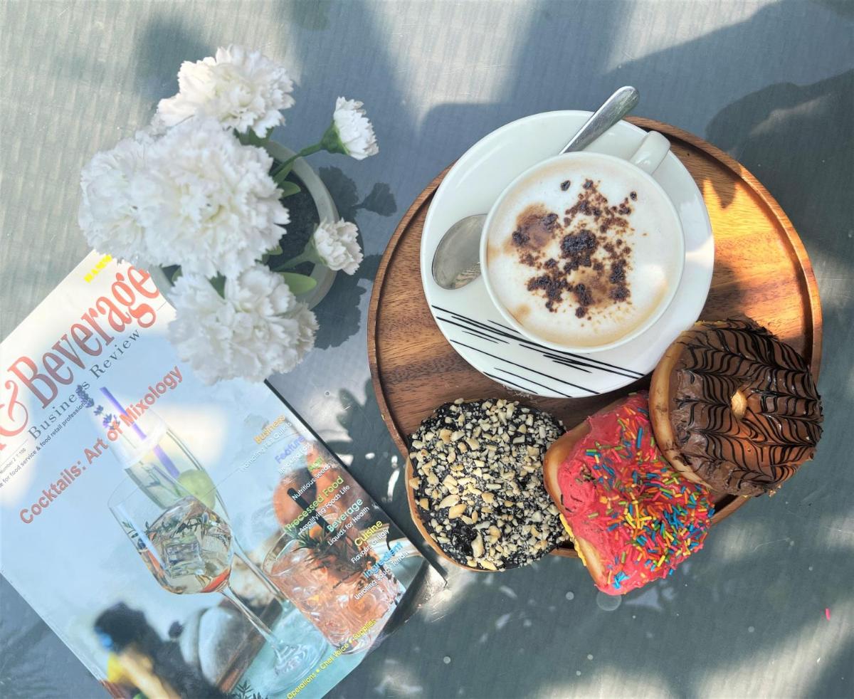 a plate of donuts and a cup of coffee and a book at Crowne Plaza Ahmedabad City Centre by IHG in Ahmedabad