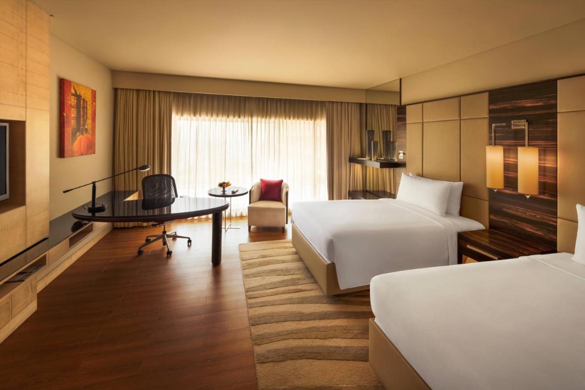a hotel room with two beds and a desk at JW Marriott Mumbai Juhu in Mumbai
