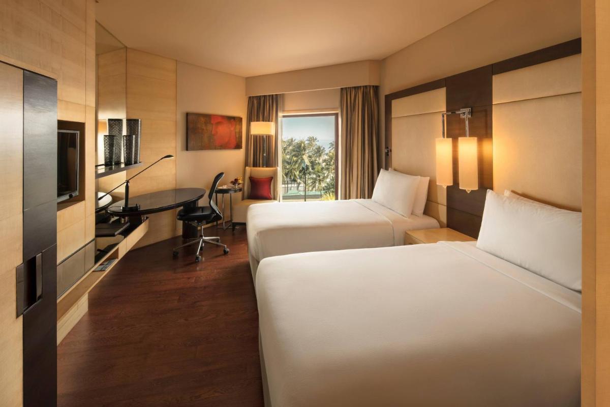 a hotel room with two beds and a desk at JW Marriott Mumbai Juhu in Mumbai