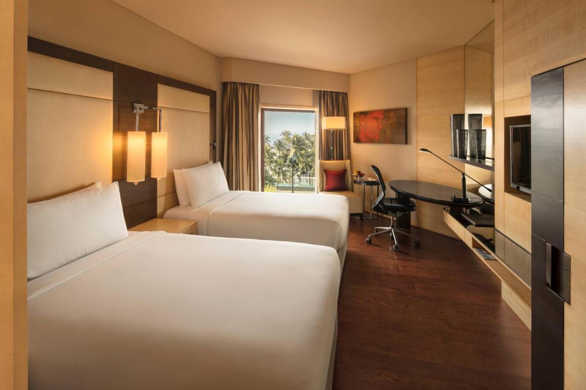 a hotel room with two beds and a desk at JW Marriott Mumbai Juhu in Mumbai