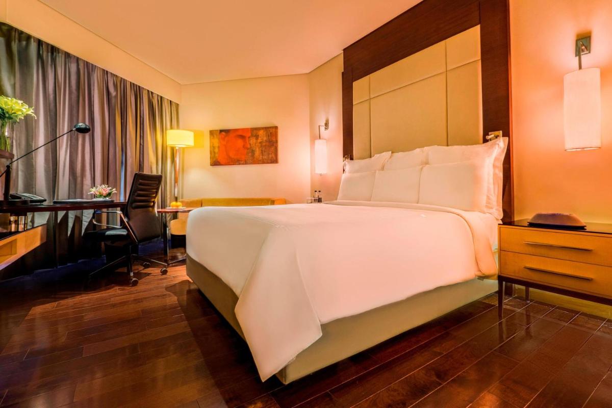 a hotel room with a large white bed and a desk at JW Marriott Mumbai Juhu in Mumbai